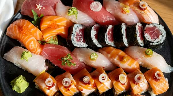 Assortment of sushi and sashimi, including tuna, salmon, white fish, and maki rolls.