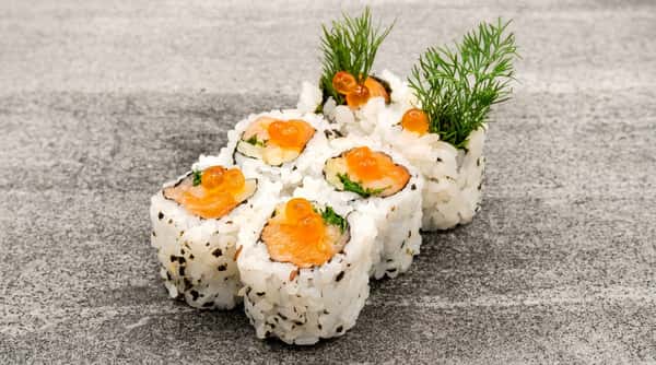 Six sushi rolls with salmon, green herbs, and orange roe on rice, arranged on a grey-flecked surface.