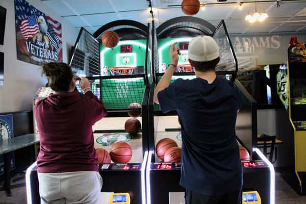 Two boys playing arcade basketball