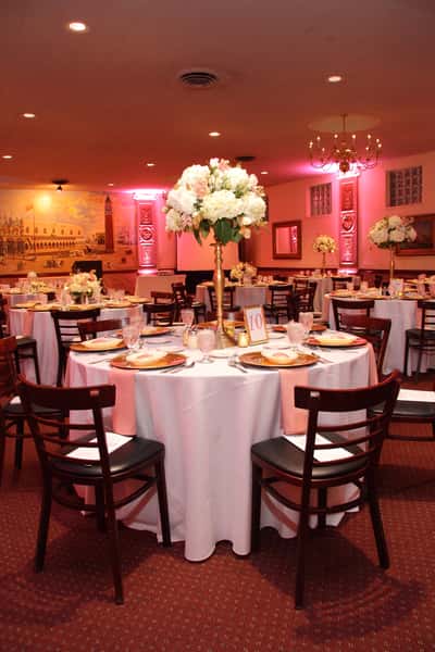 round tables set for banquet with tall rose centerpieces