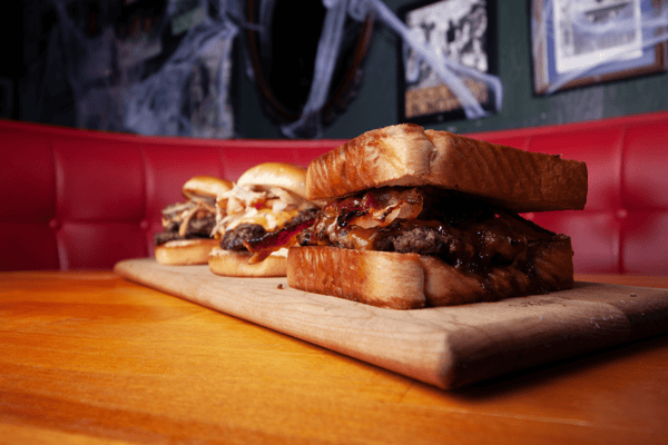 juicy gourmet burger trio on toasted buns served on wooden board at Smith's Olde Bar Atlanta American restaurant
