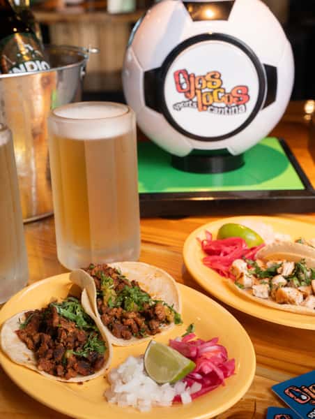 Street tacos with chopped beef, cilantro, onions, lime and pickled onions, served with cold draft beer at bar