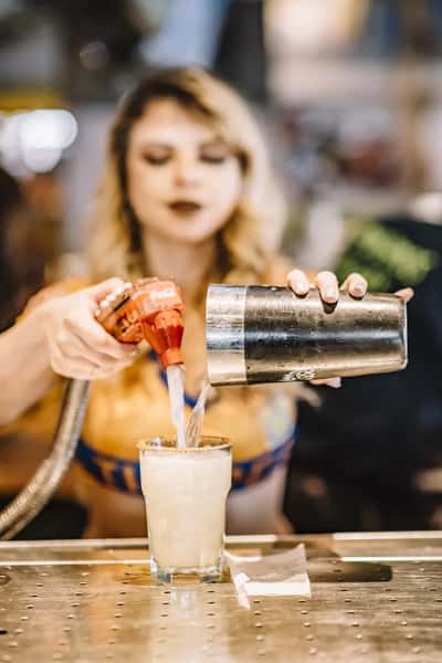 Bartender pouring frozen margarita into a salt-rimmed glass behind the bar counter