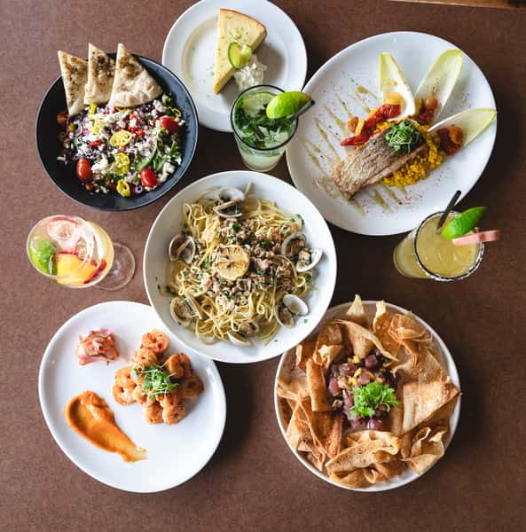 Overhead view of a full restaurant spread with drinks, salad, seafood, dessert, and poke.
