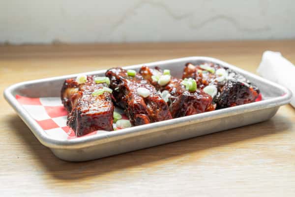 Sticky glazed BBQ ribs garnished with green onions and sesame seeds served in a metal tray at North Georgia BBQ restaurant