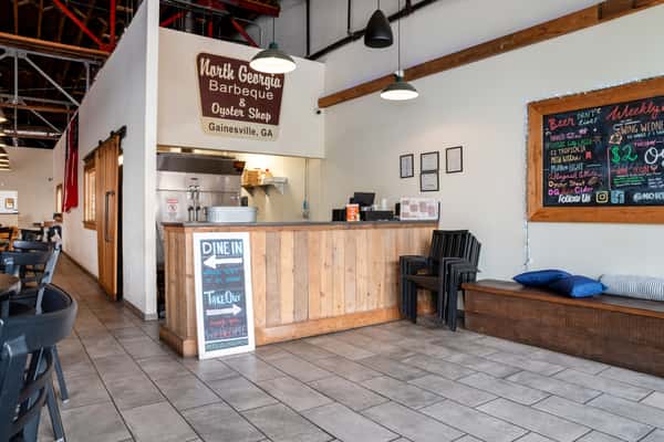 Interior of North Georgia BBQ restaurant showing the counter area with wood panels, tile flooring, and the restaurant's sign on the wall