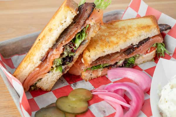 Grilled salmon BLT sandwich with fresh lettuce, tomato, and pickled onions served at North Georgia BBQ