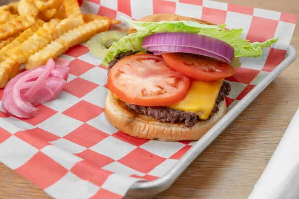 Classic diner burger with tomato, lettuce, and cheese served on red and white checkered paper in a metal tray at North Georgia BBQ restaurant