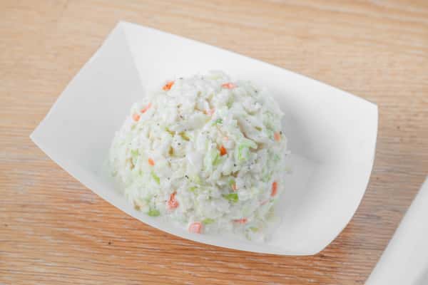 Creamy coleslaw served in a white paper boat container on a wooden surface at North Georgia BBQ restaurant