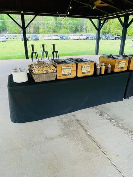 Outdoor barbecue catering setup with chafing dishes, utensils, and sauces at North Georgia Barbeque event station