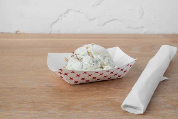 Creamy potato salad served in a white paper boat container on a wooden surface at North Georgia BBQ restaurant