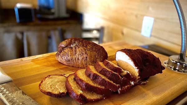 Smoked barbecue pork loin sliced on a wooden cutting board in a rustic Southern BBQ restaurant