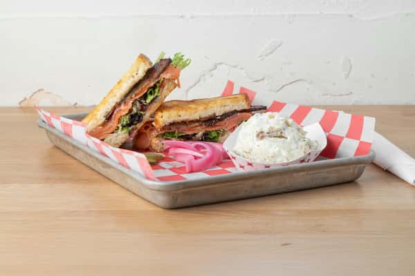 Grilled salmon BLT sandwich with fresh lettuce, tomato, and pickled onions served at North Georgia BBQ