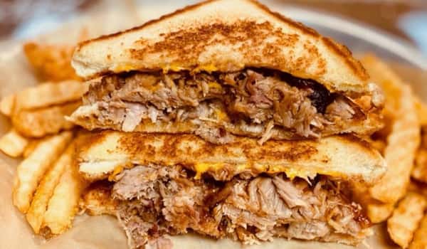 Pulled pork grilled cheese sandwich with crispy fries at a Southern barbecue restaurant