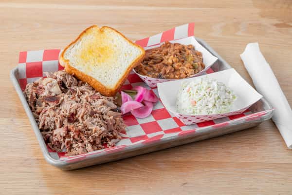 Chopped BBQ pork plate served with a slice of white bread and a side of coleslaw in a metal tray at North Georgia BBQ restaurant