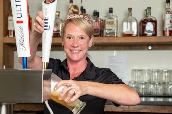 A smiling staff member at the bar area of North Georgia BBQ restaurant with beer taps and a drink visible