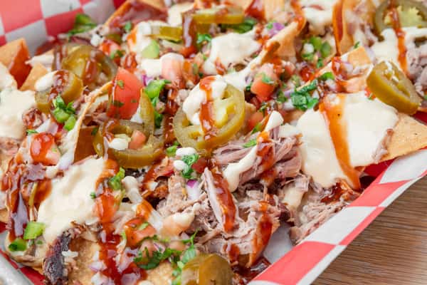 Loaded pulled pork nachos topped with cheese, jalapeños, pico de gallo, and barbecue sauce at North Georgia BBQ
