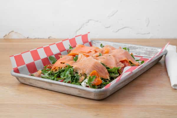 Smoked salmon slices served with fresh greens and garnishes on a wooden surface at North Georgia BBQ restaurant