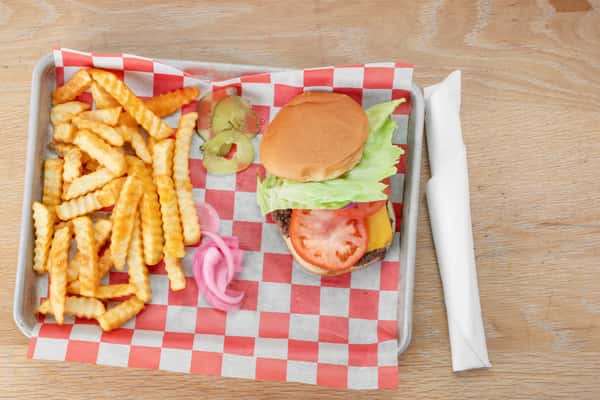 Diner burger with lettuce, tomato, and cheese served on red and white checkered paper with crinkle-cut fries in a metal tray at North Georgia BBQ restaurant
