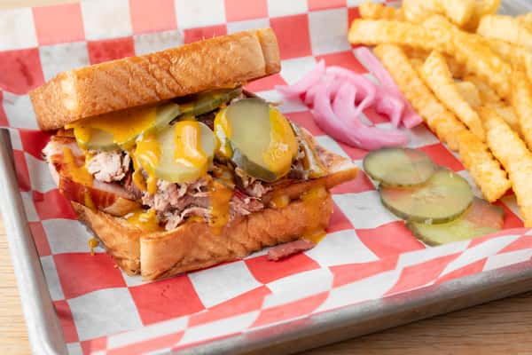 BBQ Cuban sandwich with pickled pink onions and toppings served on red and white checkered paper at North Georgia BBQ restaurant