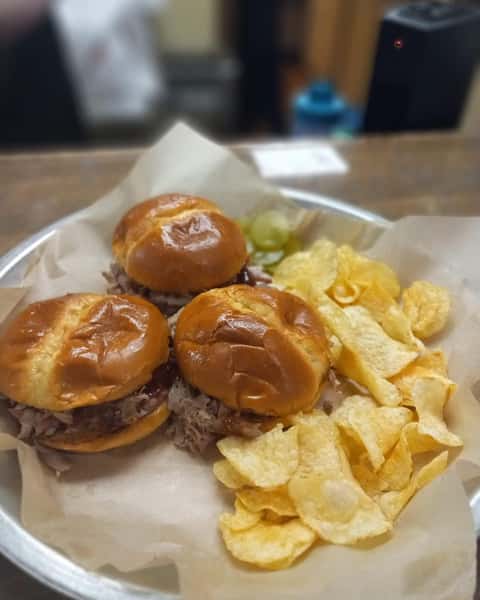 BBQ pulled pork sliders with potato chips and pickles served on a casual diner tray
