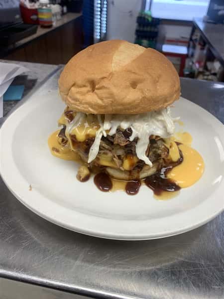 pulled pork sandwich topped with cheese sauce and cole slaw