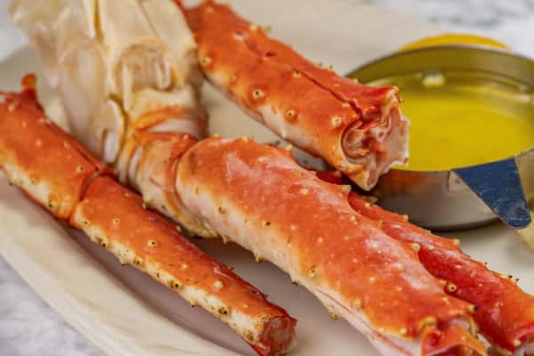 Close-up of Alaskan king crab legs with cracked shell, served alongside melted butter — a rich and indulgent seafood delicacy.