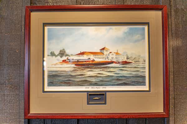 Framed painting of vintage hydroplane boats racing on the water with a historic waterfront building in the background — a nautical-themed art piece inside Sindbad's Restaurant.