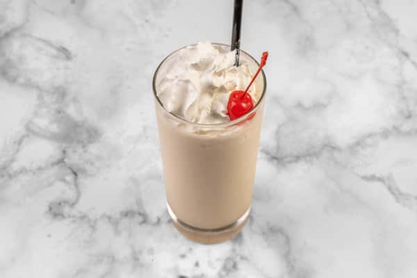 Creamy frozen cocktail topped with whipped cream and a maraschino cherry, served in a tall glass with a black straw — a sweet and refreshing beverage.