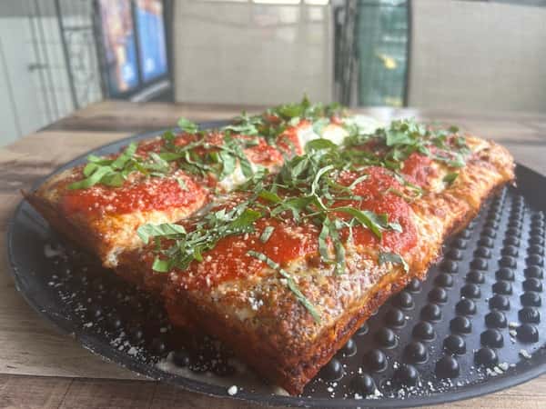 Detroit style pizza with Brick and mozarella cheeses, marinara and fresh basil