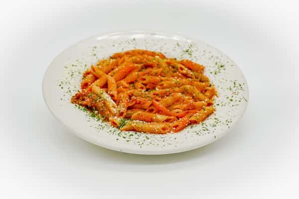 Penne pasta coated in a creamy tomato sauce, garnished with grated parmesan and a sprinkle of parsley on a white plate.
