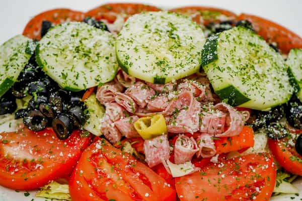 Italian antipasto salad with rolled salami, sliced cucumbers, tomatoes, olives, and pepperoncini, topped with grated cheese.