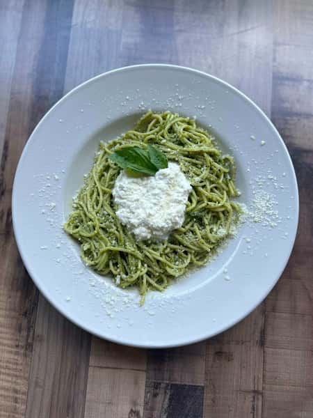 Spaghetti tossed in pesto sauce, topped with a dollop of ricotta cheese and garnished with grated Parmesan and fresh basil.
