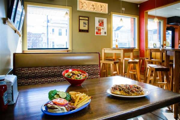 Interior shot of a philly steak sandwich, an open faced cheeseburger and salad on a table
