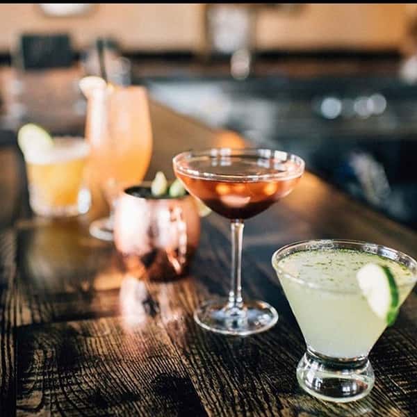 Different drinks sitting on a dark wood bar