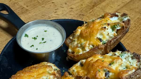 Crispy potato skins topped with melted cheese and herbs, served with a side of dipping sauce.