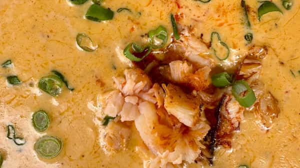 Seafood in a rich, creamy sauce topped with sliced green onions.
