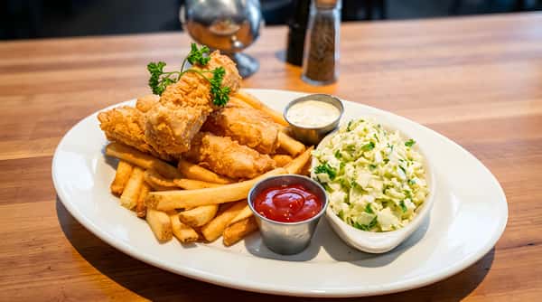 Fish and chips with coleslaw, ketchup, and tartar sauce on a white oval plate.