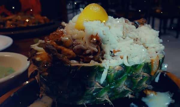 steak, rice, peppers, and onions in a pineapple