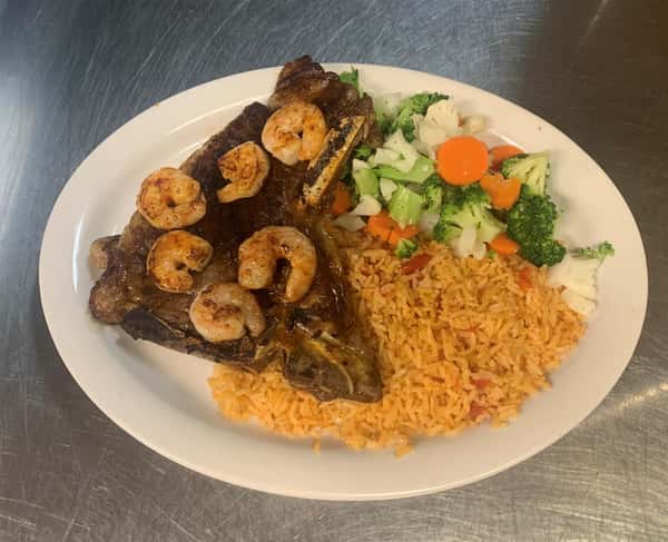 steak topped with shrimp and a side of rice and vegetables