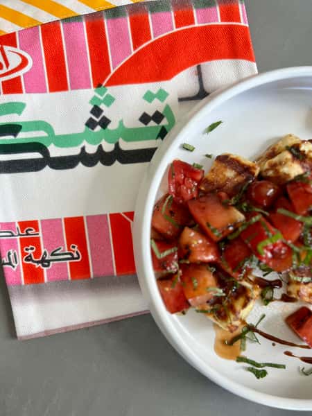 Fresh Lebanese tomato salad with herbs and feta cheese served on a colorful table setting at Lira House in Wynwood, Miami.