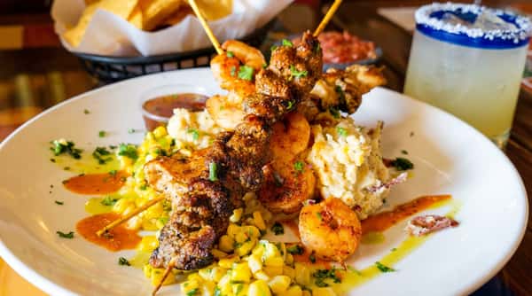 Shrimp and chicken skewers over roasted corn