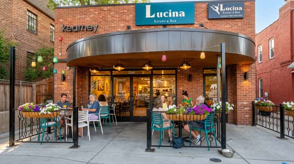 Lucina Eatery & Bar exterior with people dining on an outdoor sidewalk patio with flower boxes.