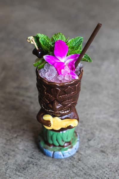 Mixed drink in a tiki cup with flower and garnish