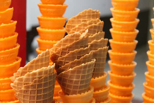 Stacks of empty ice cream cones in various sizes, with the larger cones in the background and smaller ones in the foreground.