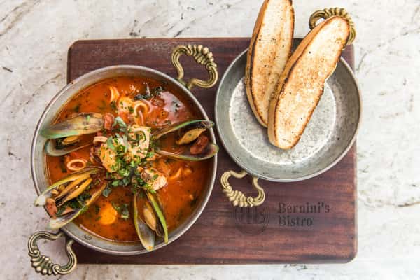 A hearty seafood soup filled with fresh shellfish, savory tomato broth, and Italian herbs, served with toasted bread for dipping.