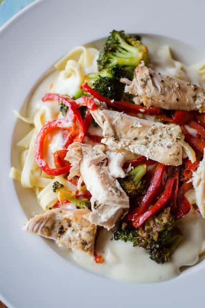 pasta with cream sauce, grilled chicken, peppers, broccoli and parmesan cheese
