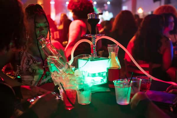Nightlife scene with colorful lighting, drinks, and people socializing around a table.