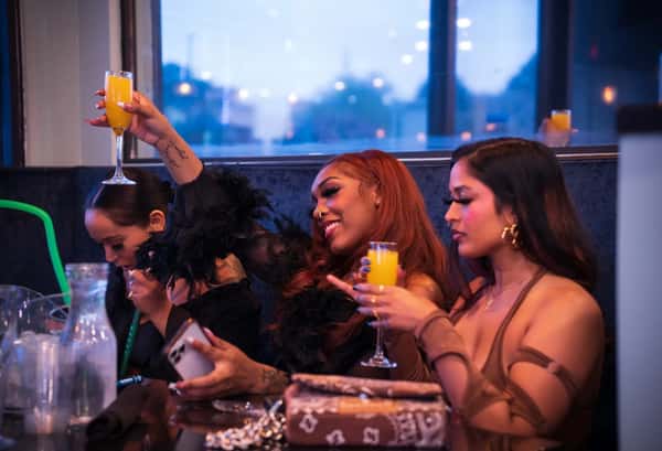 Group of women holding drinks and smiling at a table in a lounge setting.