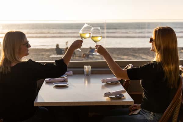 Two women cheering wine glasses